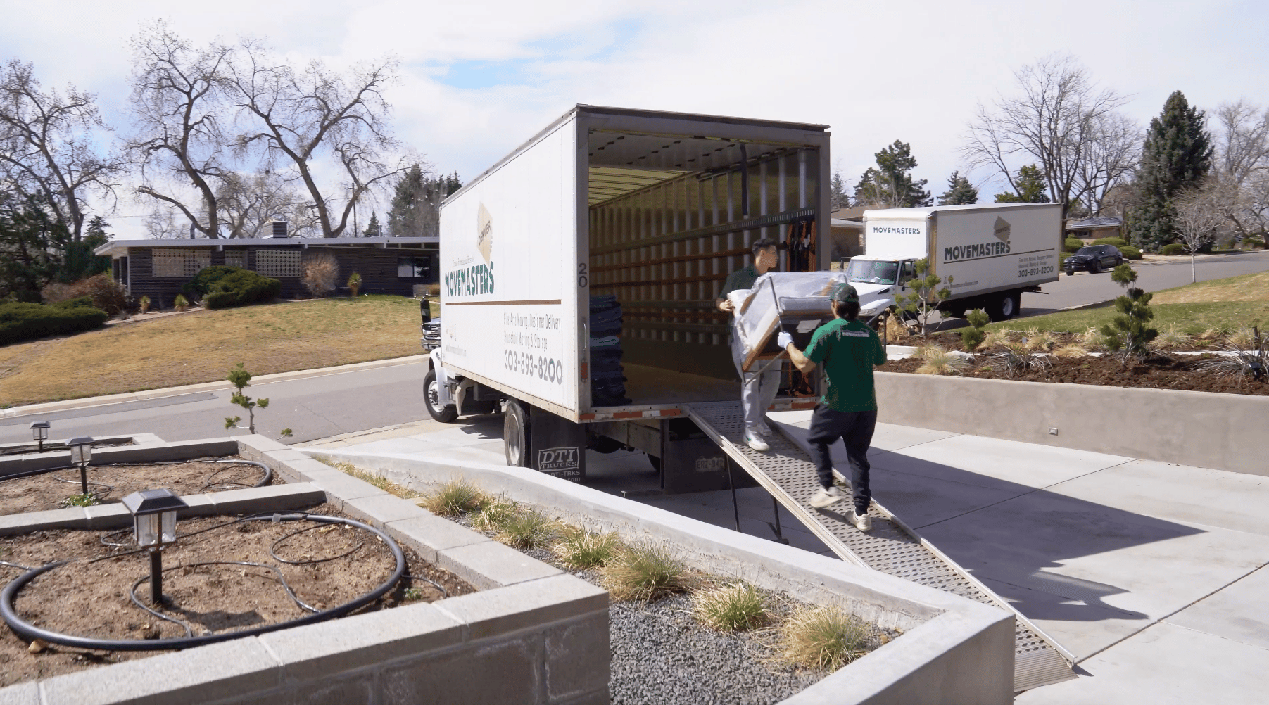 Movemasters crew loading furniture into a moving truck at a residential home